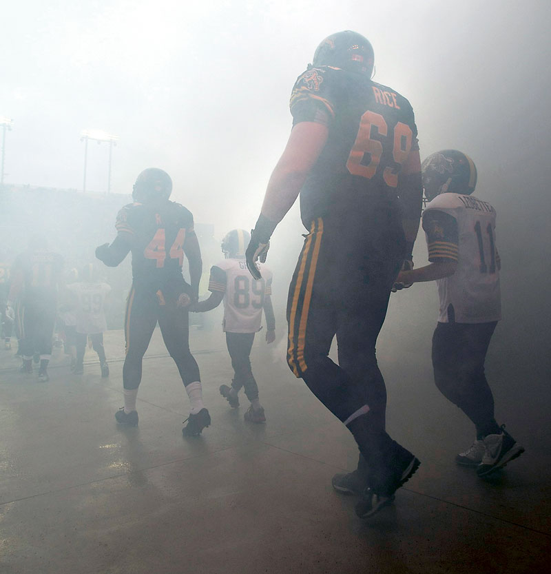 The Canadian Press
Brandonite Landon Rice of the Hamilton Tiger-Cats, escorted by a young football player, takes the field through smoke before the start of the CFL East Division final last week.