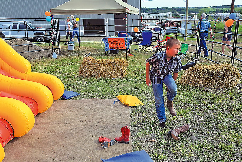 Colin Corneau/Brandon Sun
Tristan Andrews takes his boots off before playing in the children’s area at the Minnedosa Rodeo.