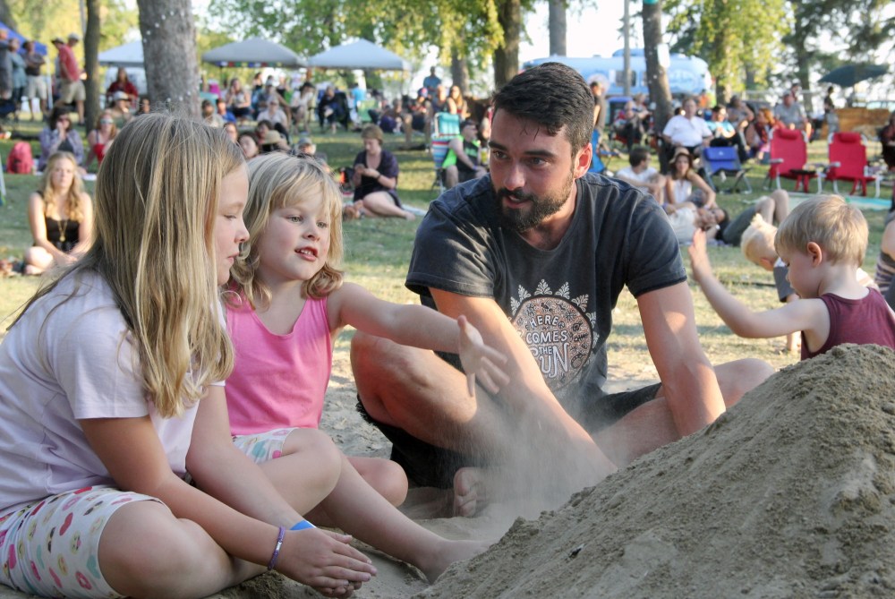 Ian Froese/The Brandon Sun
Adam Duntil tries his hand at sand building with the help of Rosannah Davidson, centre left, at the second annual Summer Lights Music Festival held Saturday on the grounds of the Keystone Centre.