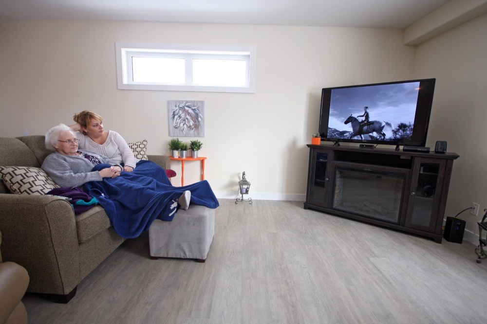 Tyler Clarke/The Brandon Sun
Daughter on Call seniors housing complex resident Ruth Molnar watches a black and white movie with health care aide Cori Behrman on Monday, a few days after the six-unit building opened.