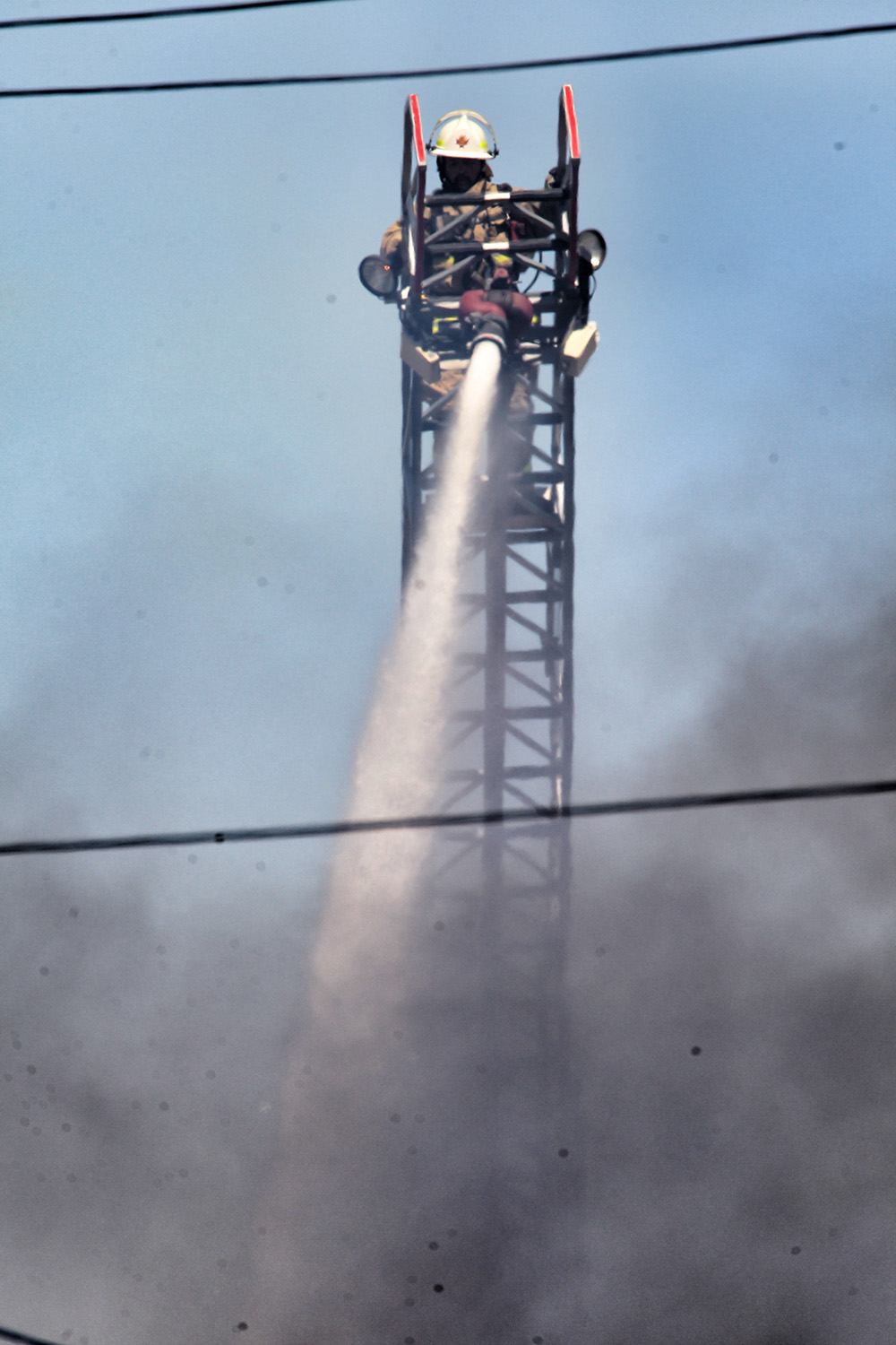 Matt Goerzen/The Brandon Sun
A firefighter works atop a crane while trying to douse flames burning up the former Code Night club and beer vendor on Rosser Avenue, across from the Brandon Sun building.