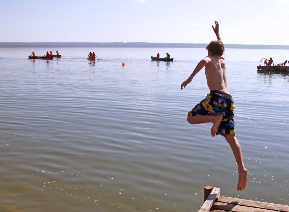 A leap of faith into the chilly waters of Clear Lake takes place during Camp Wannakumbac’s activities, while a canoe class operates in the background. (Submitted)