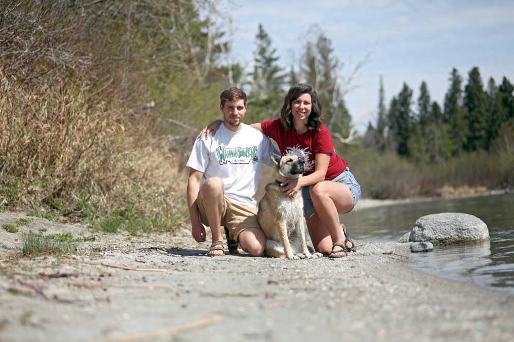 Camp Wannakumbac managers Mitch and Sarah-Anne Gustal are seen on the Clear Lake beach, which abuts the 164-acre non-profit summer campgrounds. They are pictured with Penny, a mutt who serves as camp mascot. (Tyler Clarke/The Brandon Sun)