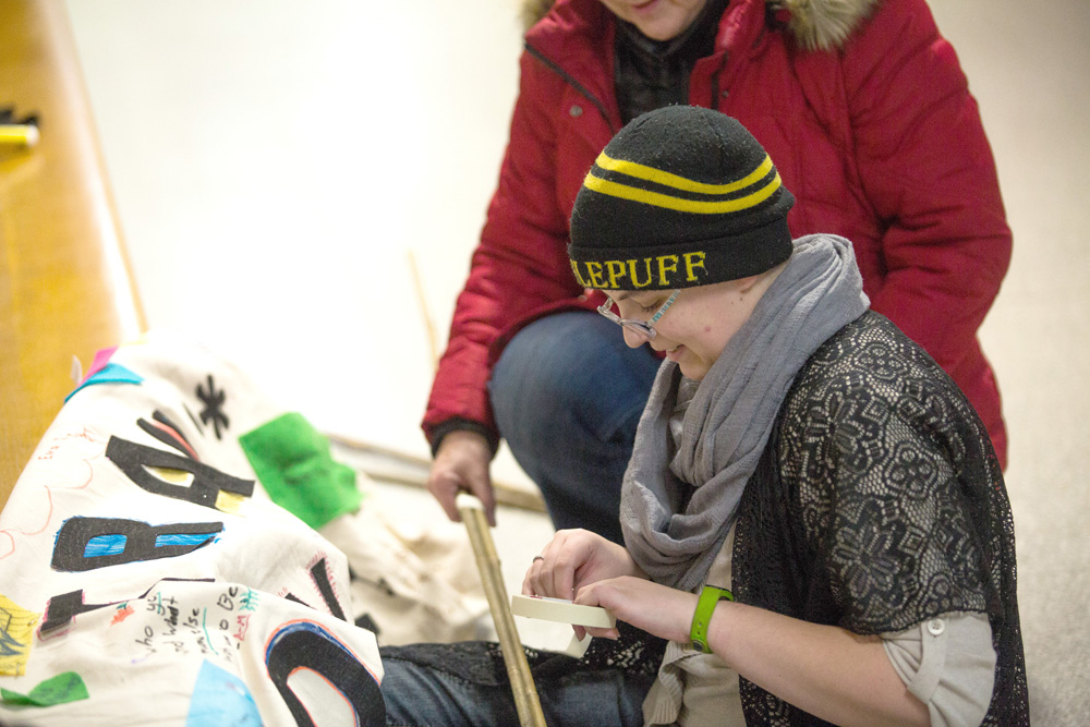Isaiah Lamontagne prepares the Trans Day of Remembrance banner for the candlelight vigil at Knox United Church Tuesday. (Chelsea Kemp/The Brandon Sun)