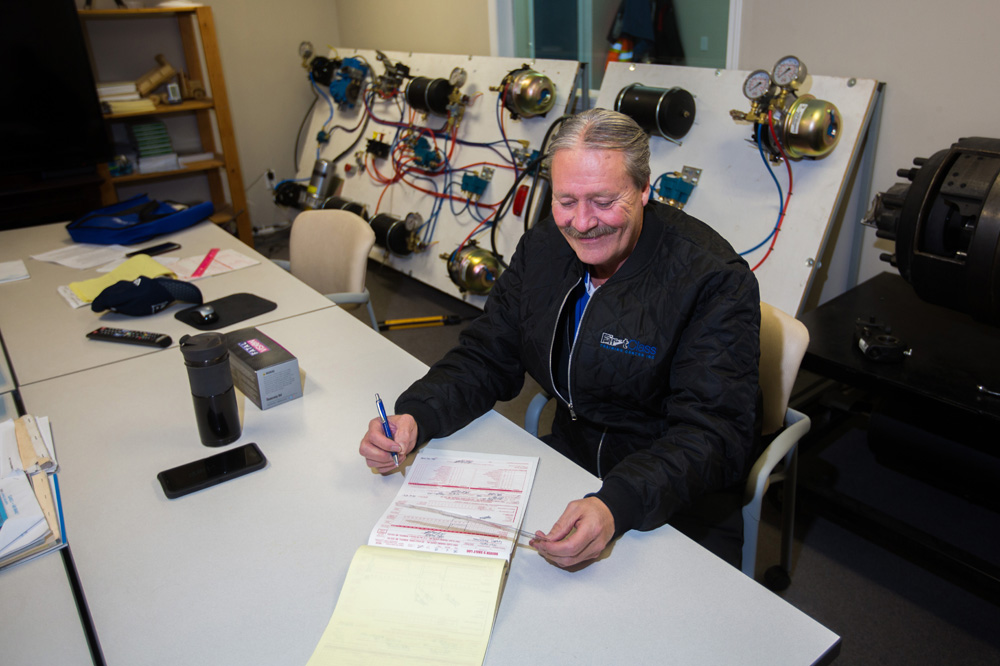 First Class Training Centre Inc. president and general manager Jim Campbell uses a trucker log book at their Cornwallis classroom on Wednesday. (Chelsea Kemp/The Brandon Sun)