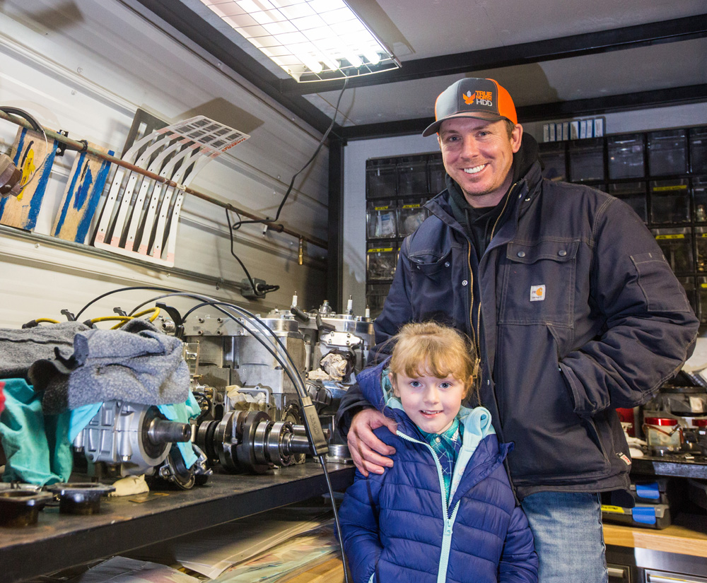 Darren Humphreys and his daughter Paisley, 6, pose for a photo in his snowmobile engine repair shop Friday. (Chelsea Kemp/The Brandon Sun)