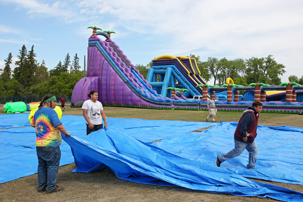 Workers set up inflatable waterslides for the Brandon Bouncy Castles summertime water park at the Keystone Centre grounds on Tuesday afternoon.  (Tim Smith/The Brandon Sun)