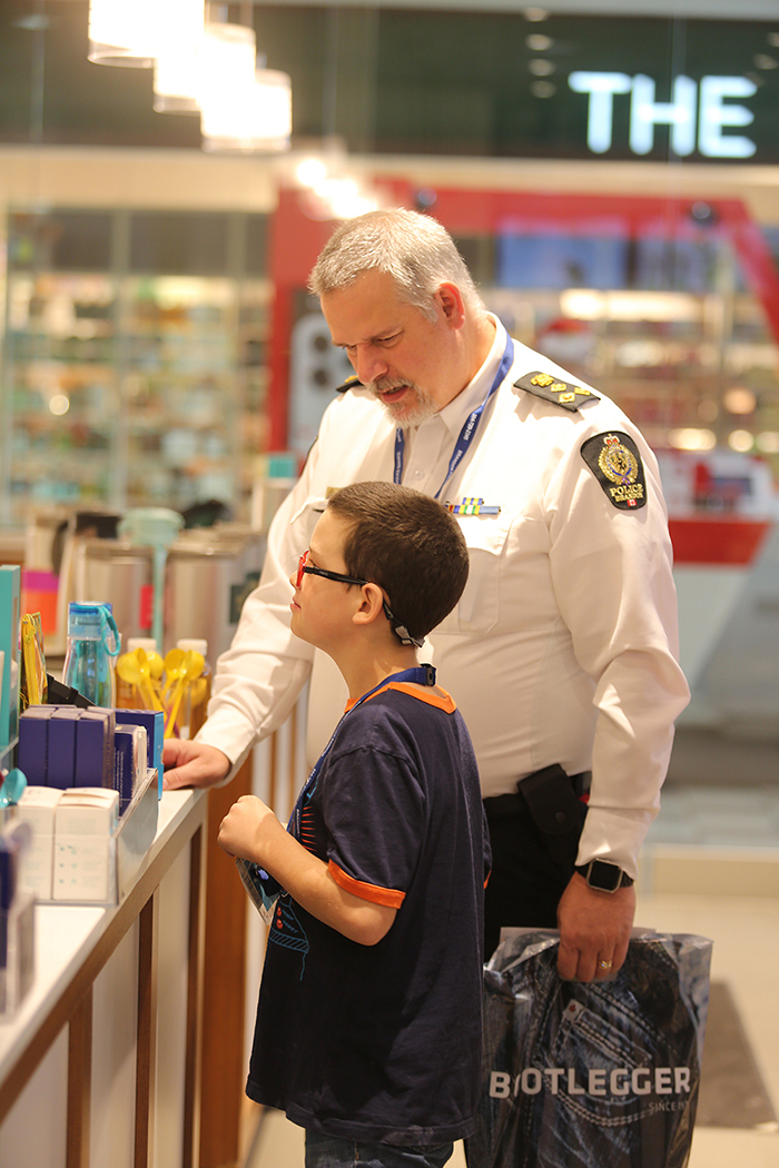 Brandon Police Service Chief Wayne Balcaen helps Ryker Martin select some holiday gifts for his friends and family at David's Tea.