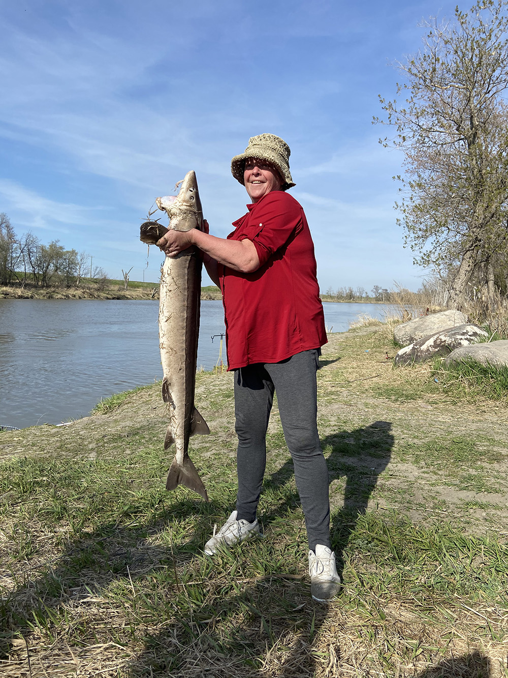 Brandon resident Pat McKenzie poses for a photo with the 53.5 inch lake sturgeon she caught Tuesday afternoon in the Assiniboine River. (Submitted)