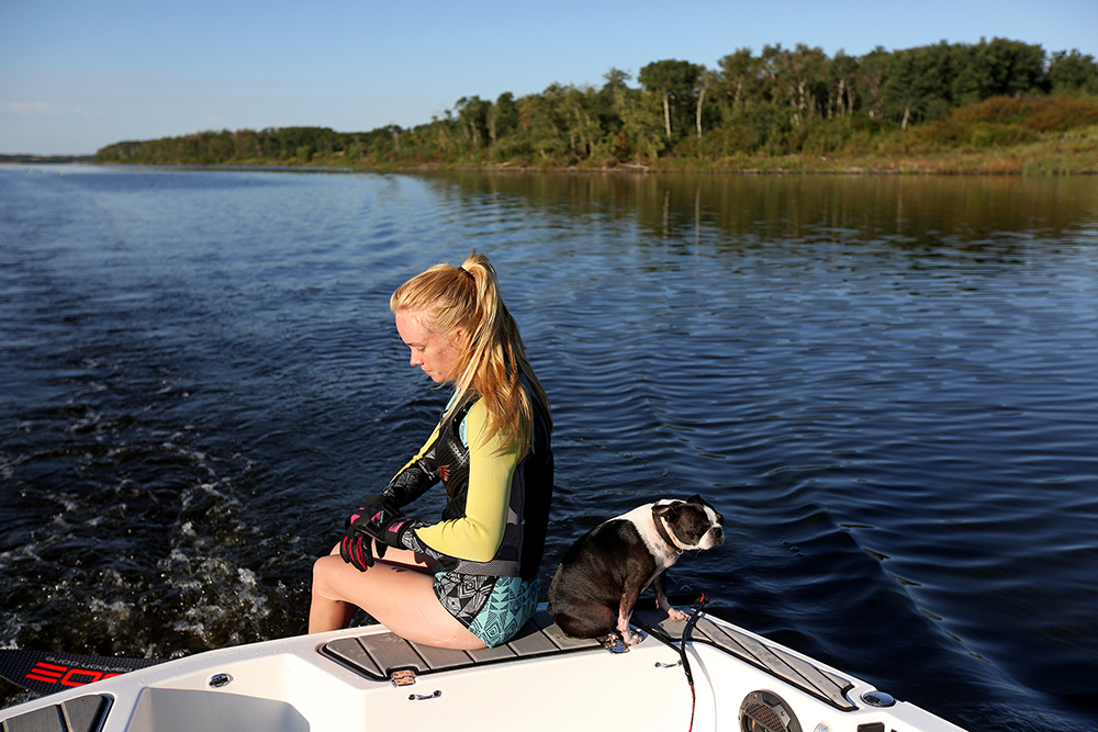 Cassandra Lepp prepares to get in the water to slalom water ski on Lake Wahtopanah as her dog Piper sits beside her on a calm and clear Tuesday morning. (Tim Smith/The Brandon Sun)