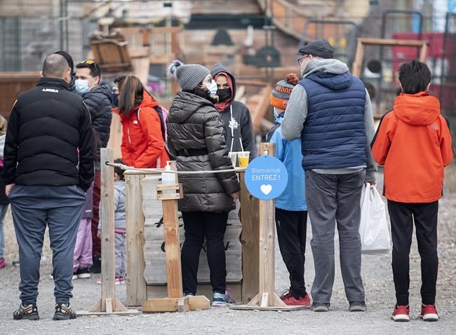 People wear face masks as they wait to enter an attraction in the Old Port in Montreal, Sunday, April 4, 2021. THE CANADIAN PRESS/Graham Hughes