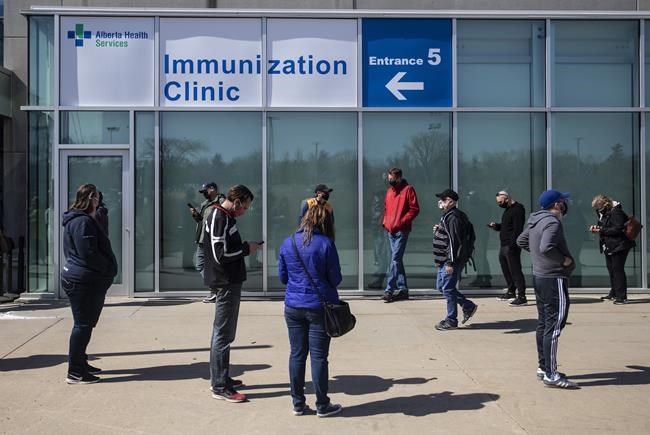 People line up outside an immunization clinic to get their Oxford-AstraZeneca COVID-19 vaccine in Edmonton, Tuesday, April 20, 2021. THE CANADIAN PRESS/Jason Franson