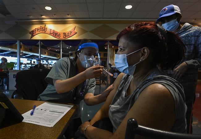 A women is vaccinated against COVID-19 at Woodbine Racetrack during the COVID-19 pandemic in Toronto on Wednesday, May 5, 2021. THE CANADIAN PRESS/Nathan Denette