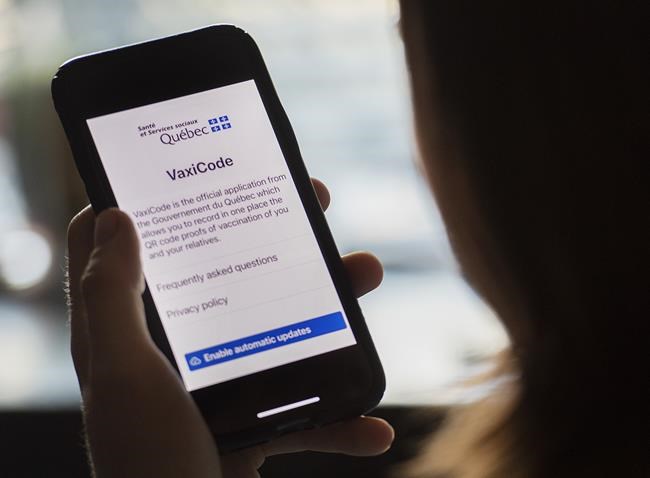 A woman looks at the Quebec government's new vaccine passport called VaxiCode on a phone in Montreal, Wednesday, Aug. 25, 2021, as the COVID-19 pandemic continues in Canada and around the world. THE CANADIAN PRESS/Graham Hughes