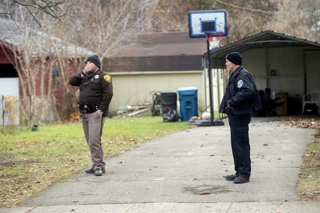 An Oakland County Sheriff's deputy, left, and an Oxford police officer search the grounds outside of the Crumbley residence while seeking James and Jennifer Crumbley, parents of alleged Oxford High School shooter Ethan Crumbley, on Friday, Dec. 3, 2021 in Oxford, Mich. (Jake May/The Flint Journal via AP)