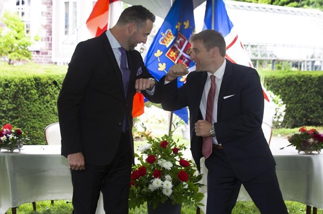 Andrew Parsons, minister of industry, energy and technology and the attorney general, left, and Premier Andrew Furey arm bump during the swearing-in ceremony of the cabinet on the grounds of Government House in St. John's on Aug. 19, 2020. THE CANADIAN PRESS/Paul Daly
