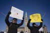 Protesters participating in a cross-country truck convoy protesting measures taken by authorities to curb the spread of COVID-19 and vaccine mandates hold signs on Parliament Hill in Ottawa on Saturday, Jan. 29, 2022. THE CANADIAN PRESS/Adrian Wyld