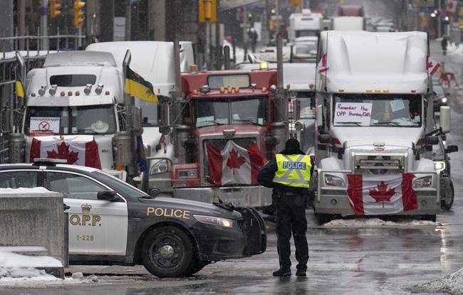 Police man a barricade in front of vehicles parked as part of the trucker protest on Tuesday, Feb. 8, 2022 in Ottawa’s downtown core. THE CANADIAN PRESS/Adrian Wyld