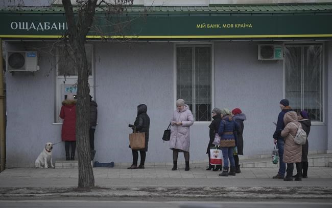 People queue to use an ATM machine outside in Sievierodonetsk, the Luhansk region, eastern Ukraine, Thursday, Feb. 24, 2022. Russian President Vladimir Putin on Thursday announced a military operation in Ukraine and warned other countries that any attempt to interfere with the Russian action would lead to