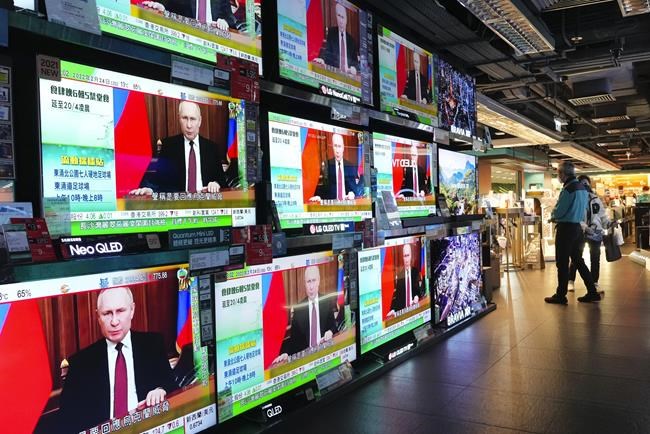 People stand by TV screens broadcasting the news of Russian troops that have launched their attack on Ukraine, in Hong Kong Thursday, Feb. 24, 2022. Russian troops launched their anticipated attack on Ukraine on Thursday, as President Vladimir Putin cast aside international condemnation and sanctions, warning other countries that any attempt to interfere would lead to