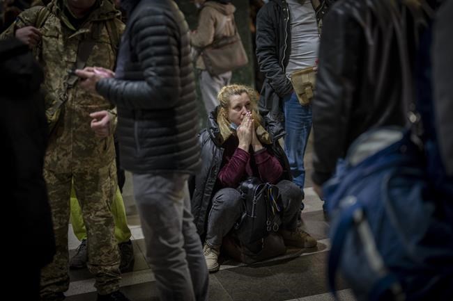 A woman reacts as she waits for a train trying to leave Kyiv, Ukraine, Thursday, Feb. 24, 2022. Russian troops have launched their anticipated attack on Ukraine. Big explosions were heard before dawn in Kyiv, Kharkiv and Odesa as world leaders decried the start of an Russian invasion that could cause massive casualties and topple Ukraine's democratically elected government. (AP Photo/Emilio Morenatti)