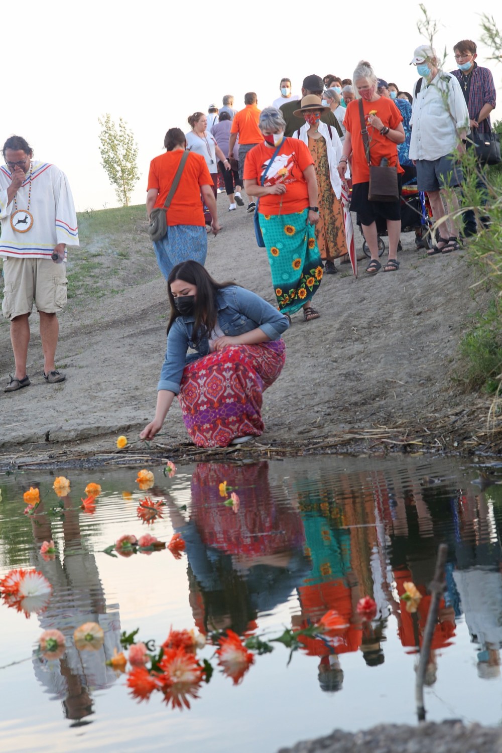 Tyler Clarke
People throw flowers into the Assiniboine River at the Riverbank Discovery Centre grounds Saturday night as part of a ceremony marking the close of a four-day and four-night sacred fire lit for those lost in the residential school system.