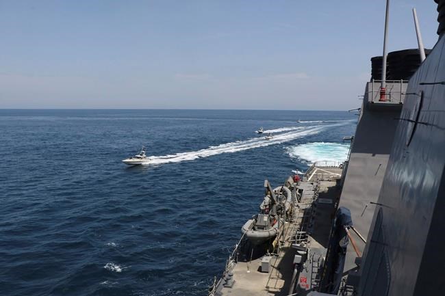 In this Wednesday, April 15, 2020, photo made available by U.S. Navy, Iranian Revolutionary Guard vessels sail close to U.S. military ships in the Persian Gulf near Kuwait. A group of 11 Iranian naval vessels made