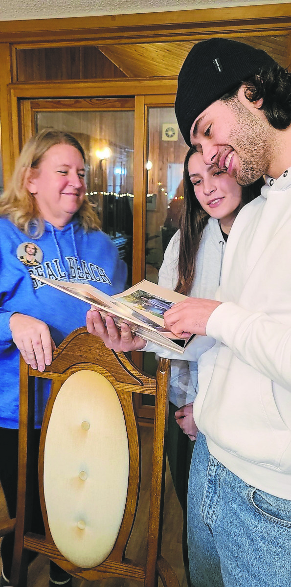 Submitted
Tracy Wilson watches as Brandon Wheat Kings forward Landon Roberts and his girlfriend Angela Pasakas look at a photo book she prepared for him about his time with the Tri-City Americans and her family.