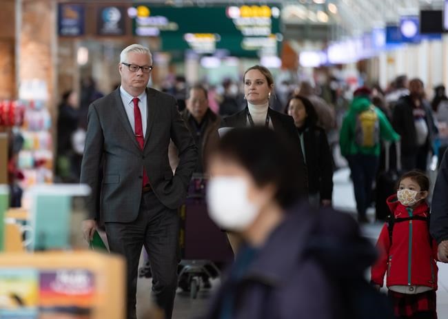 Craig Richmond, back left, President & CEO of Vancouver Airport Authority, arrives for a news conference at Vancouver International Airport, in Richmond, B.C., Tuesday, March 17, 2020. The Vancouver Airport Authority is pulling the plug on some major infrastructure projects because it says the ongoing decline in air travel caused by the COVID-19 pandemic mean they are no longer immediately needed. THE CANADIAN PRESS/Darryl Dyck