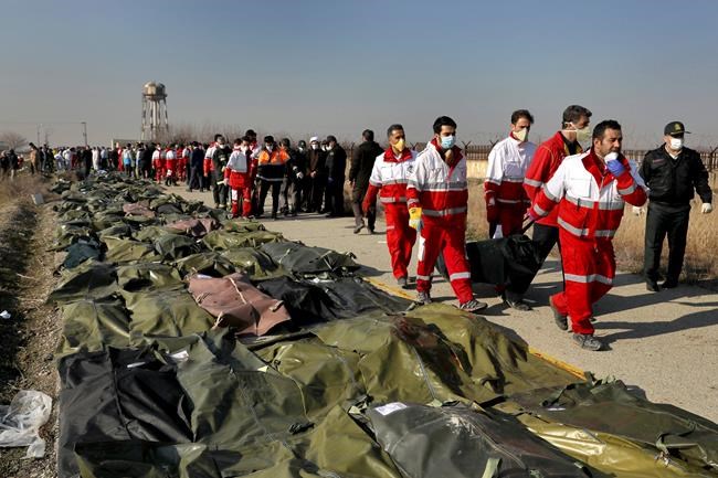 FILE - In this Wednesday, Jan. 8, 2020 file photo, rescue workers carry the body of a victim of a Ukrainian plane crash in Shahedshahr, southwest of the capital Tehran, Iran. Two U.S. officials said Thursday that it was “highly likely” that an Iranian anti-aircraft missile downed a Ukrainian jetliner late Tuesday, killing all 176 people on board. President Donald Trump is suggesting he believes Iran was responsible. (AP Photo/Ebrahim Noroozi, File)