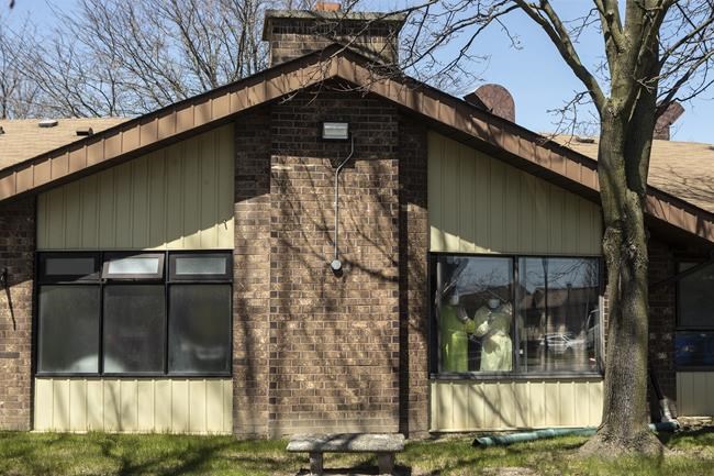 Staff members stand at a window as they watch a parade of well wishers as they drive through Orchard Villa Care home, in Pickering, Ont. on Saturday, April 25, 2020. Experts say the path to fixing long-term care in Canada after the pandemic is not clear, but all agree it starts with improving work conditions for carers. THE CANADIAN PRESS/Chris Young