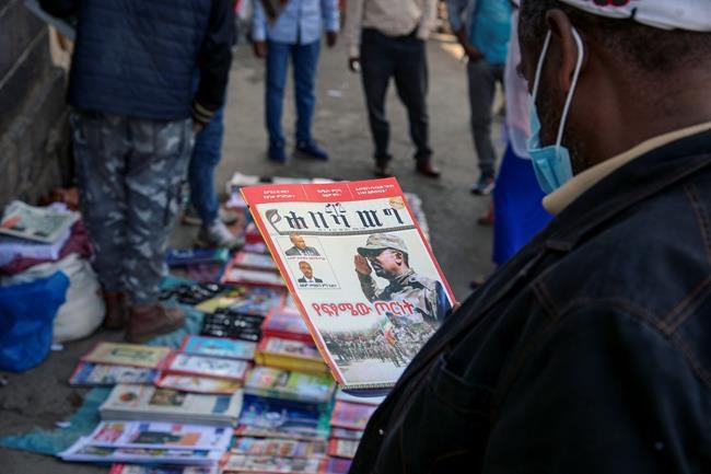 Ethiopians read newspapers and magazines reporting on the current military confrontation in the country, one of which shows a photograph of Prime Minister Abiy Ahmed, on a street in the capital Addis Ababa, Ethiopia Saturday, Nov. 7, 2020. Ethiopia moved Saturday to replace the leadership of the country's defiant northern Tigray region, where deadly clashes between regional and federal government forces are fueling fears the major African power is sliding into civil war. (AP Photo/Samuel Habtab)