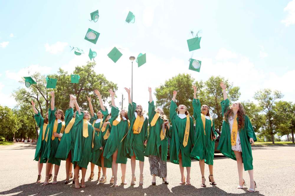 A group of graduating friends throw their mortarboards in the air after receiving their diplomas during École secondaire Neelin High School’s drive-thru graduation ceremony at the Keystone Centre grounds on Monday. (Tim Smith/The Brandon Sun)