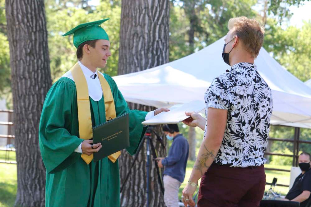 École Secondaire Neelin High School teacher Ryan Flannery hands Wil Miller Harms his yearbook during Monday’s graduation ceremony at the Keystone Centre grounds in Brandon. (Kyle Darbyson/The Brandon Sun)