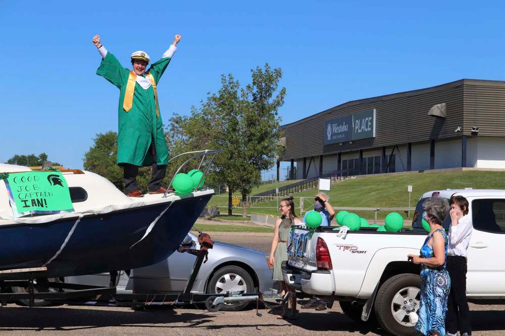 Ian Cox strikes a victory pose on a boat alongside his family during Monday’s École secondaire Neelin High School graduation ceremony, which took place outside the Keystone Centre in Brandon. Cox was one of more than 110 students who took part in this “drive-thru” ceremony, which was put together in accordance with the province’s latest health restrictions. Now that he has officially graduated from Neelin, Cox told the Sun that he plans to attend the Asper School of Business in Winnipeg. (Kyle Darbyson/The Brandon Sun)