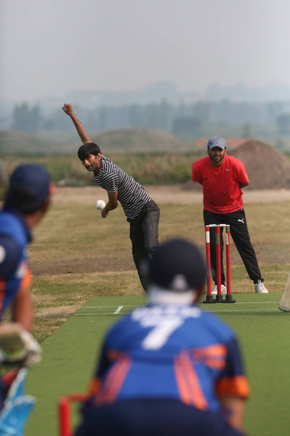 Bowler Dinesh Patel delivers the cricket ball with a winding arm during an exhibition game in August 2021. (File)