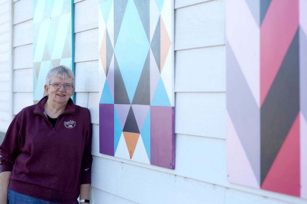 Artist Kathy Levandoski is seen next to her three favour barn quilts she created, which have been installed on the side of the Kelwood Community Centre. (Tyler Clarke/The Brandon Sun)