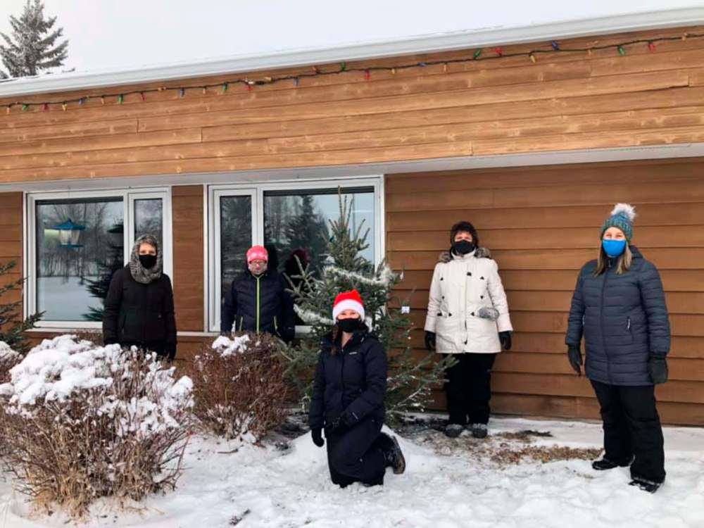 Rachelle Chwaluk, middle, and some volunteers plant Christmas trees outside the Rossburn Health Centre on Wednesday in order to bring some holiday cheer to the residents of this personal care home. (Submitted)