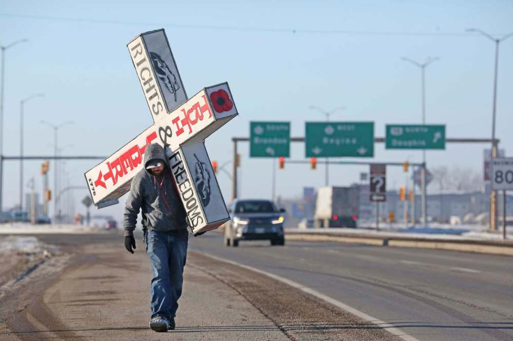 Warren Michael, who calls himself “The Old Man” on his gofundme page, is ‘walking a cross Canada’ with a literal cross on his back, to raise money for “veterans, clean drinking water for First Nations, mental health issues, autism awareness, and cancer research.” He’s seen here on his way out of Brandon as he walks eastbound on the Trans-Canada Highway on Friday afternoon. (Matt Goerzen/The Brandon Sun)
