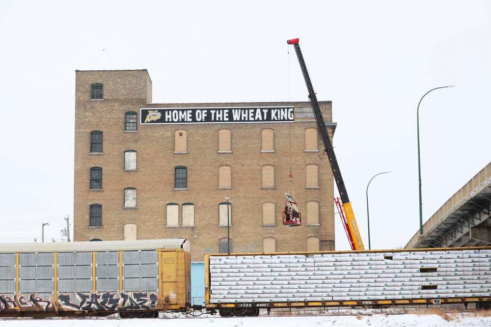 Workers began the task of taking down the Home of the Wheat Kings signs from the former Kullberg’s Furniture Warehouse on Wednesday. The sign will head to its new home at the Keystone Centre until a decision is made on what to do with the piece of Brandon history. (Photos by Tim Smith/The Brandon Sun)