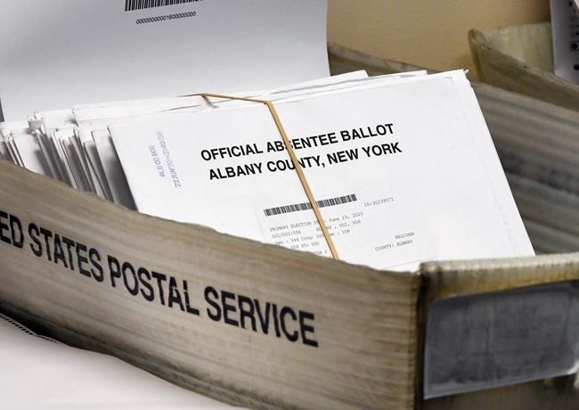 FILE - In this June 30, 2020, file photo, a box of absentee ballots wait to be counted at the Albany County Board of Elections in Albany, N.Y. New York will allow voters to request absentee ballots for the general election because of coronavirus under a new state law signed Thursday, Aug. 20. Lawmakers passed the bill last month, and voting rights groups have been calling on Gov. Andrew Cuomo to sign the legislation for weeks. (AP Photo/Hans Pennink, File)