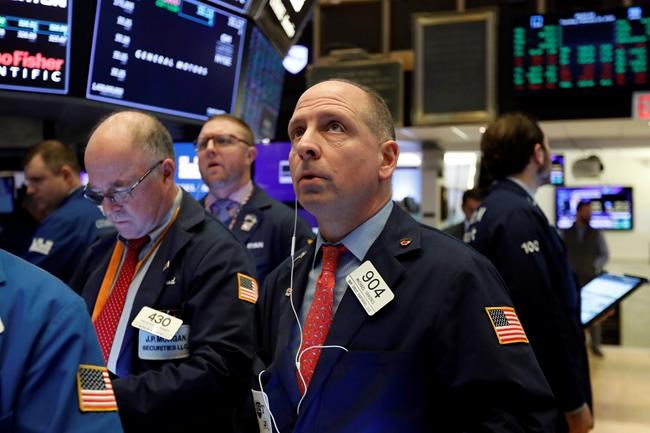 Michael Urkonis, center, works with fellow traders on the floor of the New York Stock Exchange, Tuesday, Feb. 25, 2020. Stocks opened slightly higher on Wall Street as the market claws back some of the ground it lost in a dramatic sell-off a day earlier. (AP Photo/Richard Drew)