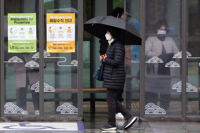 A woman wearing face mask passes by posters about precautions against new coronavirus at a bus station in Seoul, South Korea, Tuesday, Feb. 25, 2020. China and South Korea on Tuesday reported more cases of a new viral illness that has been concentrated in North Asia but is causing global worry as clusters grow in the Middle East and Europe. (AP Photo/Ahn Young-joon)