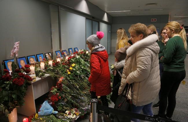 People look at a memorial at Borispil international airport outside in Kyiv, Ukraine, Thursday, Jan. 9, 2020, for the flight crew members of the Ukrainian 737-800 plane that crashed on the outskirts of Tehran. The crew of a Ukrainian jetliner that crashed in Iran, killing all 176 people on board, never made a radio call for help and was trying to turn back for the airport when the burning plane went down, an initial Iranian investigative report said Thursday. (AP Photo/Efrem Lukatsky)