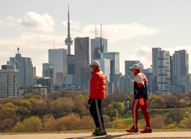 Two men in masks walk in the late afternoon sun in Toronto on Thursday, May 7, 2020. With warmer weather set to return physical distancing in public spaces will become more difficult. THE CANADIAN PRESS/Frank Gunn
