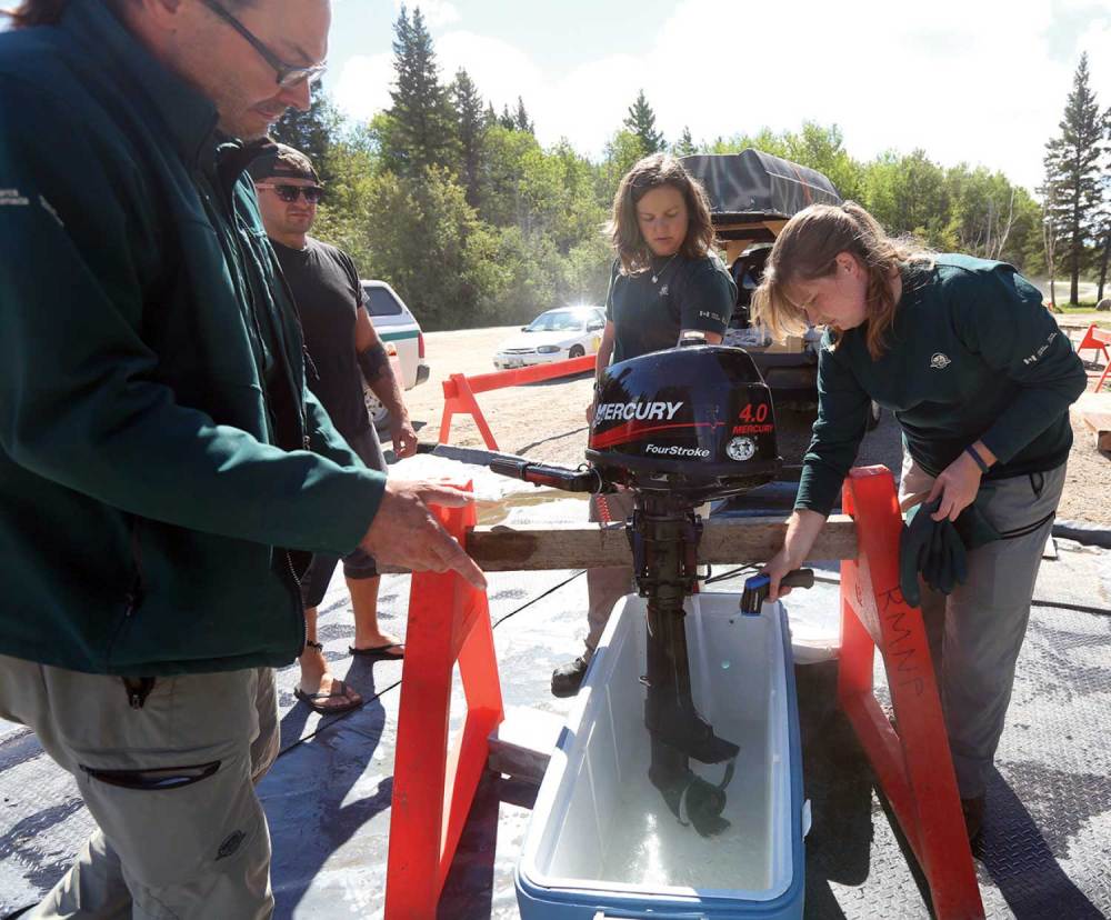 Parks Canada staff run hot water through a boat motor at an inspection site in Riding Mountain National Park.