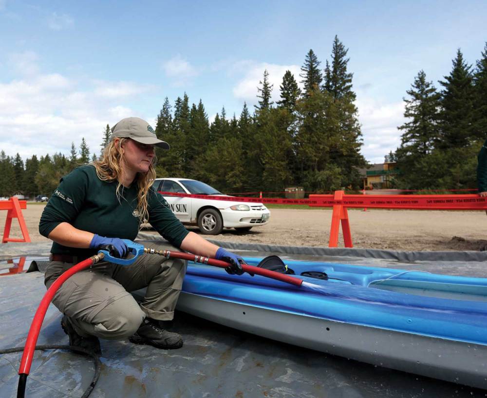 Parks Canada employee Avalon Shavers runs hot water over a kayak in order to prevent the spread of any invasive species in Riding Mountain National Park.