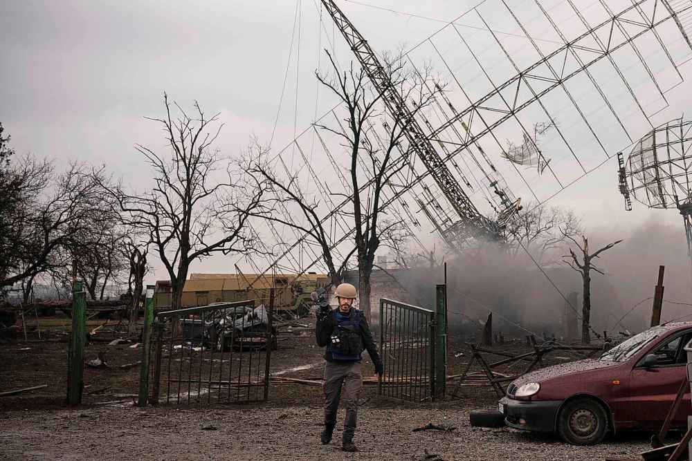 Associated Press videographer Mstyslav Chernov walks amid smoke rising from an air defense base in the aftermath of a Russian strike in Mariupol, Ukraine, Thursday, Feb. 24, 2022. (Evgeniy Maloletka / The Associated Press)