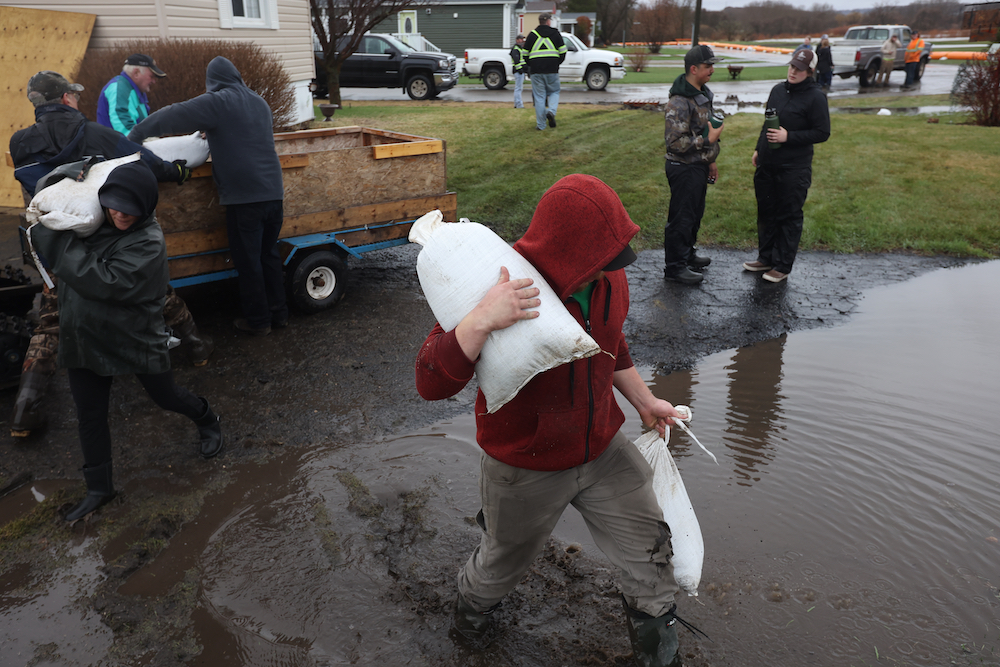 Tim Smith/The Brandon Sun
A volunteer trudges through mud as they carry sandbags to a protective dike in Minnedosa.