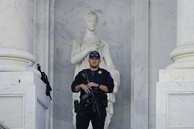 A heavily armed police officer stands guard outside the U.S. Capitol building, Thursday, June 9, 2022, in Washington. The House select committee will have its first public hearing in its investigation of the Jan. 6 attack on the U.S. Capitol. The hearing is expected to reveal the findings of a year-long investigation. (AP Photo/Julio Cortez)